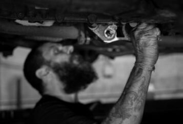 Mécanicien inspectant un pneu et le système de suspension d’une voiture dans un atelier de réparation automobile à Québec appelé Ténéré Auto.